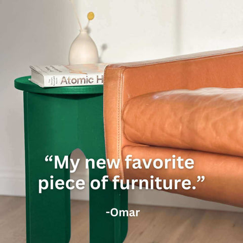 Unfinished side table in green with leather chair, showcasing books and quote about the table's appeal.
