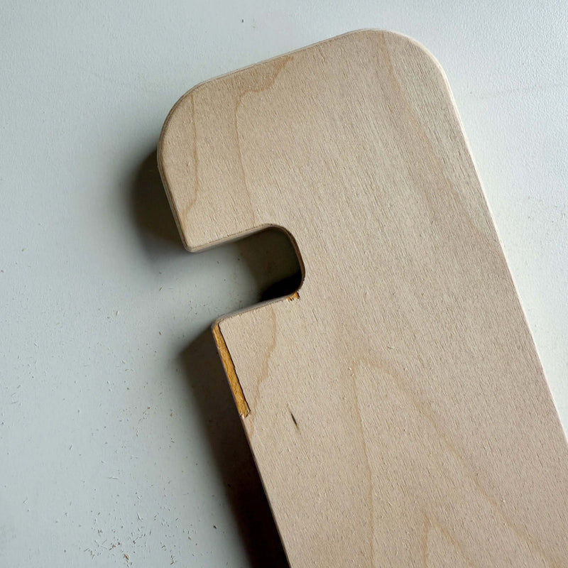 Close-up of a unique piece of blemished wood furniture with a cutout and small imperfections.