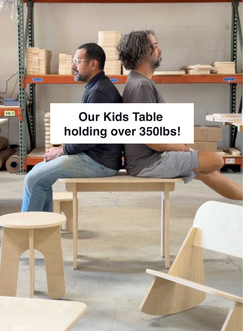 Two men sitting back to back on a strong eco-friendly kids table, showcasing its durability holding over 350lbs.