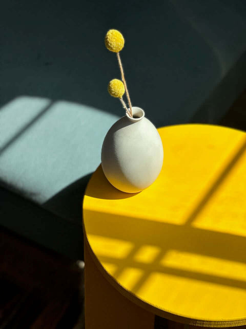 A vase with yellow flowers on a mustard yellow table, showcasing mustard yellow as a vibrant accent in home decor.