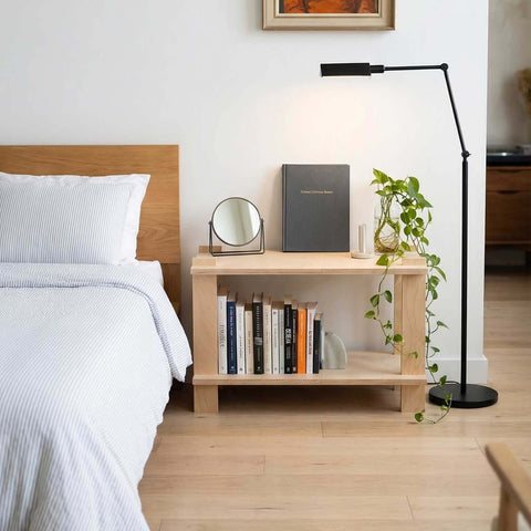 How to Furnish Your Airbnb on a Budget (Without Sacrificing Style) featuring a minimalistic bedroom setup with a bookshelf and stylish lamp.