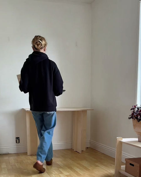 Finished birch plywood desk against a sunlit apartment wall with laptop