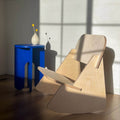 Modern Mini Rocker kids chair in sunlight beside blue side table with vase of flowers.