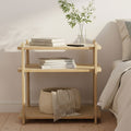 Wooden night stand with books and a plant next to a bed in a bedroom setting