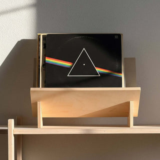 Wooden shelf with a vinyl record and books against a gray wall